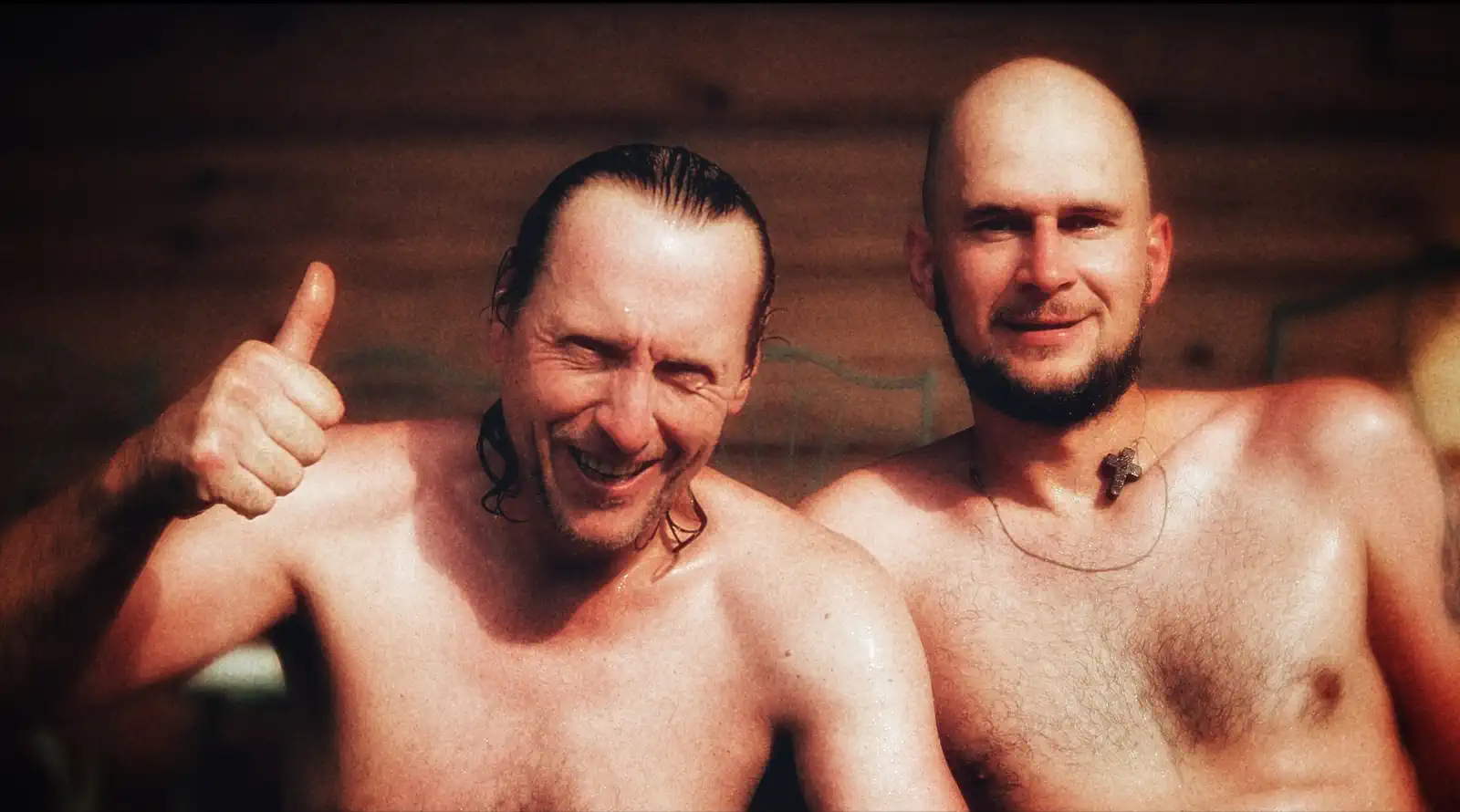 Two people smiling after sauna, warm wooden background